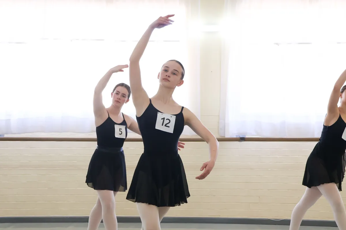 Two dancers with their arms raised taking part in an audition.